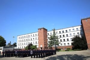 Uroczystość na placu apelowym OPP w Katowicach. Widoczni policjanci, którzy złożyli ślubowanie. Na dalszym planie budynek na terenie OPP