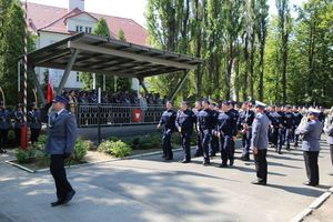 Defilada kończąca uroczystość. Na pierwszym planie maszerują policjanci, którzy złożyli ślubowanie, na dalszym planie trybuna z gośćmi uroczystości