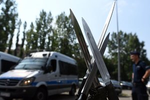 Na pierwszym planie broń policjantów z kompanii honorowej, w tle radiowozy