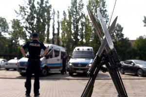 Na pierwszym planie broń policjantów z kompanii honorowej, w tle policjant i radiowozy