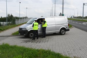 Policjanci w trakcie kontroli drogowej. Widoczny m.in. nieoznakowany radiowóz