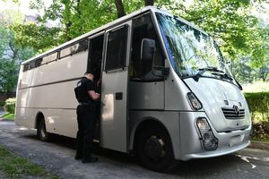 Policjant przed autobusem do przewozu zatrzymanych