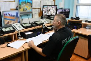 Policjant odbierający telefon przed ekranami monitoringu