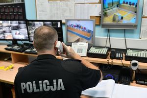 Policjant odbierający telefon przed ekranami monitoringu