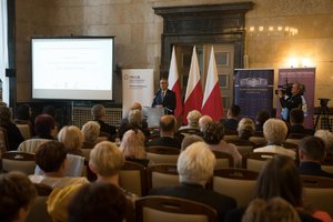 Zdjęcie kolorowe. Przedstawia uczestników konferencji oraz Stanisława Szweda - Sekretarza Stanu w Ministerstwie Rodziny, Pracy i Polityki Społecznej.