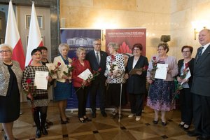 Zdjęcie kolorowe. Zdjęcie przedstawia wyróżnione za działalność społeczną uczestniczki konferencji, oraz od lewej poseł na Sejm RP Maria Nowak,  Stanisław Szwed - Sekretarz Stanu w Ministerstwie Rodziny, Pracy i Polityki Społecznej, wicewojewoda śląski Jan Chrząszcz.