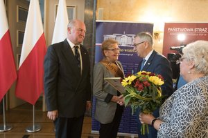 Zdjęcie kolorowe. Zdjęcie przedstawia wyróżnioną w konkursie Aktywny senior Renate Böhm ze Stowarzyszenia na rzecz odnowy i rozwoju lokalnego sołectwa Rudno, oraz wręczających wyróżnienie Stanisława Szweda - Sekretarza Stanu w Ministerstwie Rodziny, Pracy i Polityki Społecznej, poseł na Sejm RP Marii Nowak, wicewojewodę śląskiego Jana Chrząszcza.