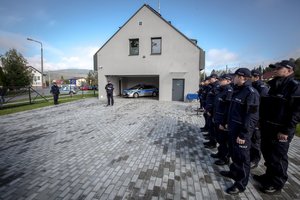 zdjęcie kolorowe: Komendant Wojewódzki Policji w Katowicach podczas przemówienia, na zdjęciu także umundurowani policjanci, w tle Posterunek Policji w Milówce