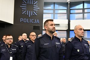 umundurowani policjanci biorący udział w odprawie, w tle gwiazda policyjna na ścianie pomieszczenia