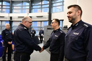 generał gratuluje policjantowi, wręczając mu akt powołania na stanowisko