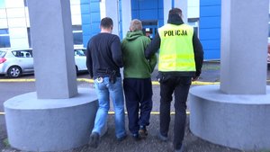 policjanci prowadzą zatrzymanego mężczyznę