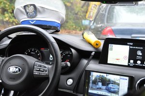 zdjęcie kolorowe: widok z wnętrza radiowozu nieoznakowanego, na  podszybiu szpaka policyjna i urządzenie do badanie  trzeźwości.