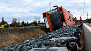 Przewrócony autobus przy torowisku.