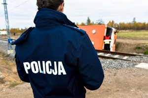 Na pierwszym planie policjantka stojąca plecami. W tle przewrócony autobus.