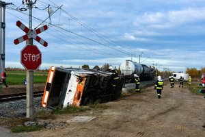 Przewrócony autobus przy torowisku i służby ratunkowe