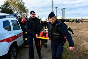 Policjanci i strażacy przenoszą osobę poszkodowaną.