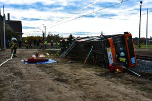 Strażacy przy przewróconym autobusie.