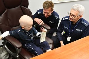 Kubuś siedzący na miejscu naczelnika, obok niego Zastępca Komendanta Wojewódzkiego Policji, insp. Mariusz Krzystyniak oraz naczelnik