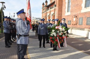 Przedstawiciele kierownictwa Policji idą w stronę pomnika z kwiatami