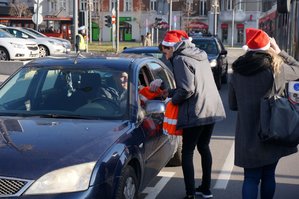 młodzież w czapkach mikołajowych rozdaje kierowcom upominki