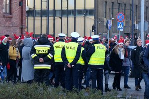 umundurowani policjanci oraz funkcjonariusz straży pożarnej podczas działań z młodzieżą w mikołajowych czapkach