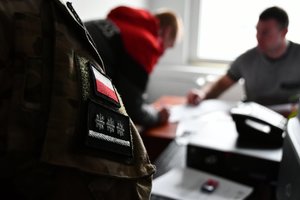 Zatrzymany podpisuje dokumenty w obecności policjantów