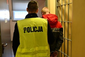 Na zdjęciu widać policjanta, obok którego stoi zatrzymany mężczyzna