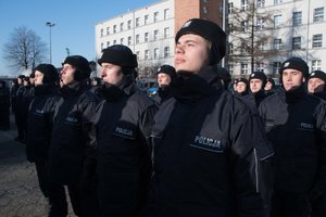 Zdjęcie kolorowe. Uroczystość ślubowania. Widoczni nowi policjanci