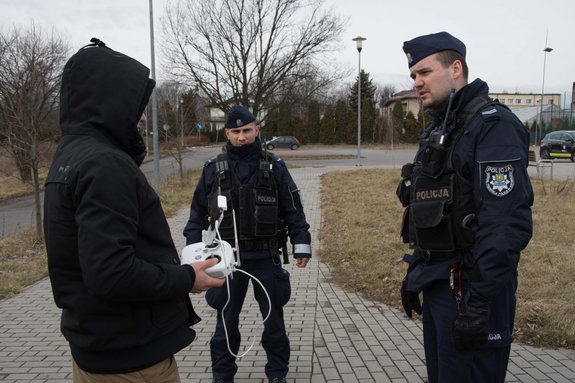 Zdjęcie kolorowe. Widoczny operator drona oraz policjanci