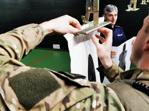 Policjant wieszający tarczę strzelecką na wyciąg