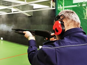 Policjant celujący z broni gładkolufowej do tarczy