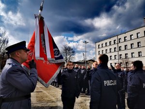 Nowo przyjęci policjanci podczas uroczystego ślubowania.  Z lewej sztandar.