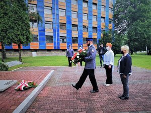 Uczestnicy uroczystości składają wieniec przed grobem.