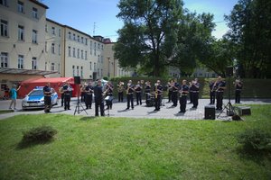 Zdjęcie kolorowe. Policjanci i policyjni muzycy występujący przed szpitalem