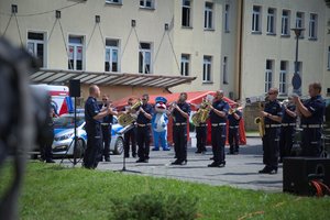 Zdjęcie kolorowe. Policjanci i policyjni muzycy występujący przed szpitalem