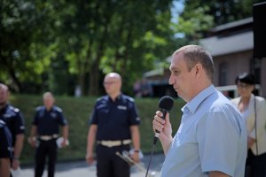 Zdjęcie kolorowe. Policjanci i przedstawiciel szpitala przed szpitalem