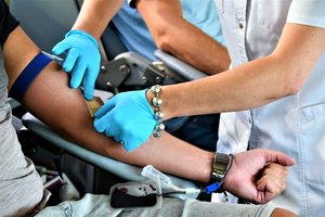 Pielęgniarka w ambulansie nakleja plaster na rękę jednemu z dawców