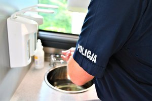 Umundurowany policjant dezynfekuje dłonie