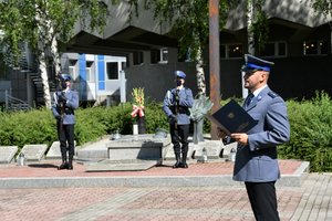 Policjanci stojący przed pomnikiem.