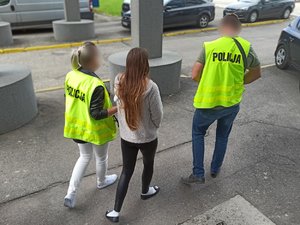Zdjęcie kolorowe. Policjanci prowadzą osobę zatrzymaną