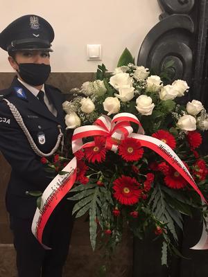 Zdjęcie kolorowe. Tablica Gloria Victis. Uroczyste złożenie kwiatów pod tablicą w obecności policyjnej warty honorowej.
