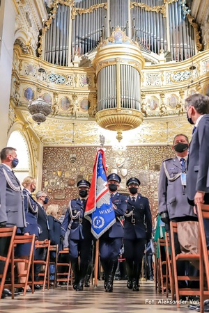 Zdjęcie kolorowe. Wnętrze kaplicy. Widoczny policyjny poczet sztandarowy.