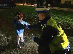 Policjant daje dziecku element odblaskowy.