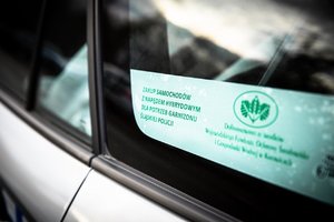 Szyba radiowozu, na niej naklejka z napisem zakup samochodów z napędem hybrydowym dla potrzeb garnizonu śląskiej Policji