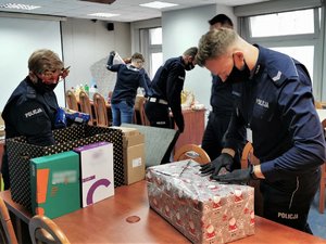 Policjanci pakują prezenty w ozdobny papier.