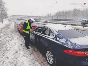 Policjant rozmawia z kierowcą osobówki.