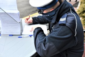 Umundurowany policjant wypełnia dokumenty przed oddaniem krwi.