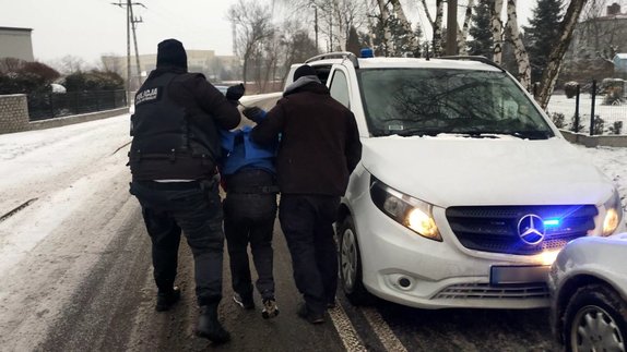 Policjanci prowadzą zatrzymanego do radiowozu