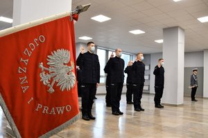 Sztandar Komendy Wojewódzkiej Policji w Katowicach, w tle ślubujący policjanci.