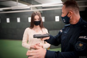 Zdjęcie kolorowe. Widoczna Miss Polski 2020 oraz policjant prezentujący pistolet. Autor zdjęcia: Michał Piątek